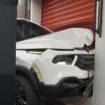 Após colisão, carro sobe em calçada e danifica porta de loja